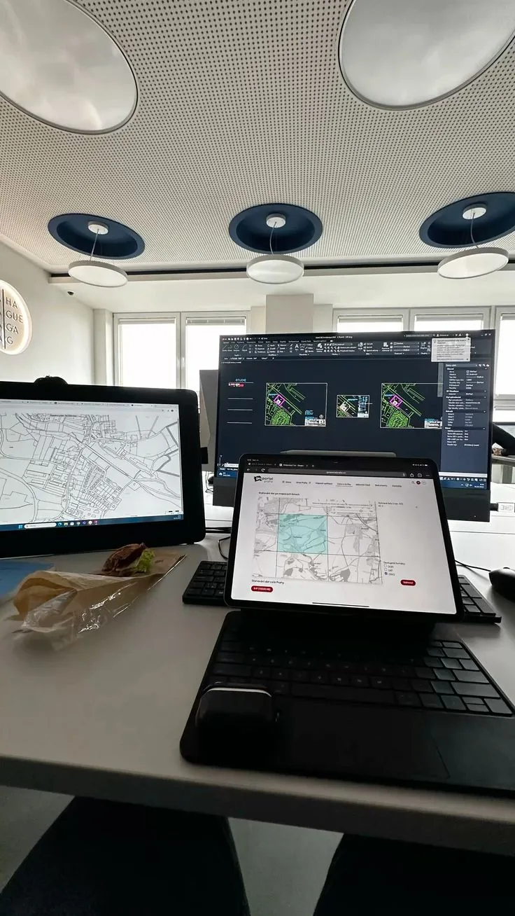 Multi-screen GIS workstation showing map views alongside a tablet